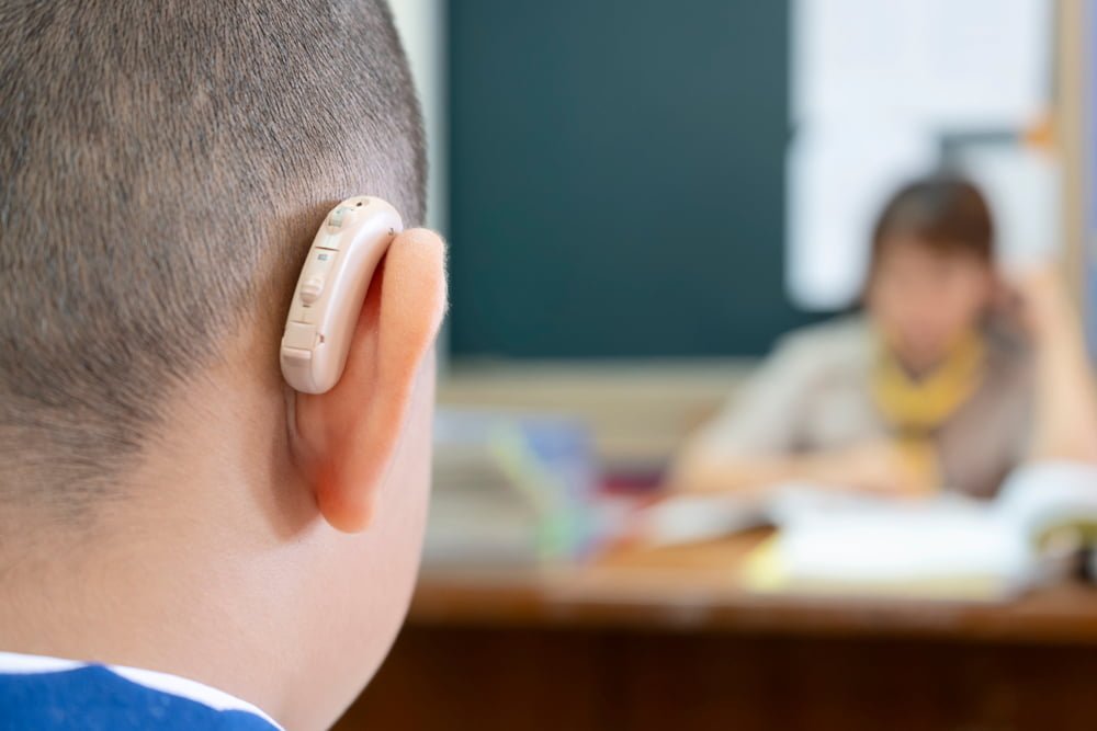 Young boy in class wearing a hearing aid