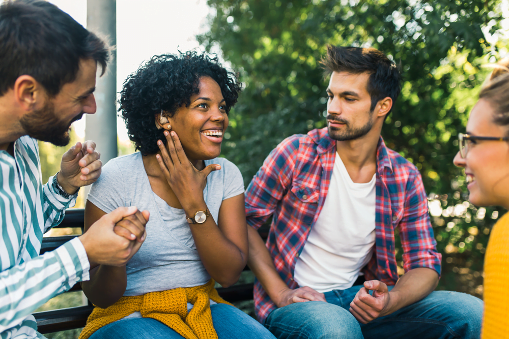 Young woman wearing hearing aid having a conversation with a group of people