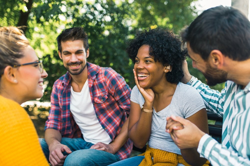 Woman wearing hearing aid having a conversation with her friends in the park