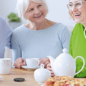 A group of senior individuals having a conversation over a cup of tea, using a Roger microphone