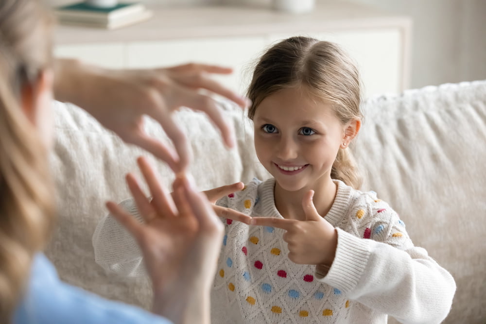 Smiling child communicating non-verbally with adult