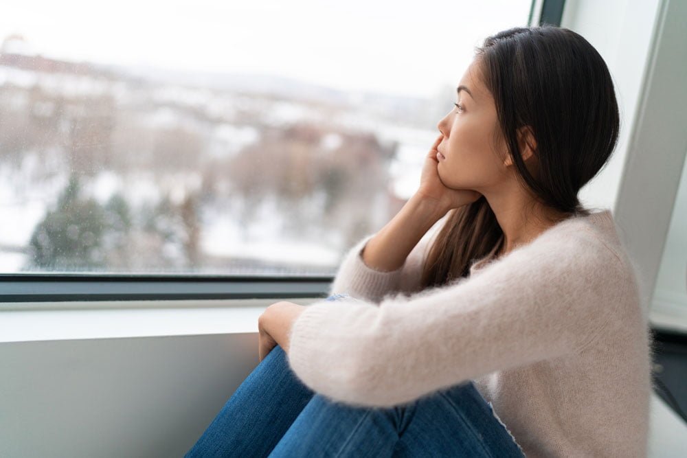 Sad looking woman sitting next to window