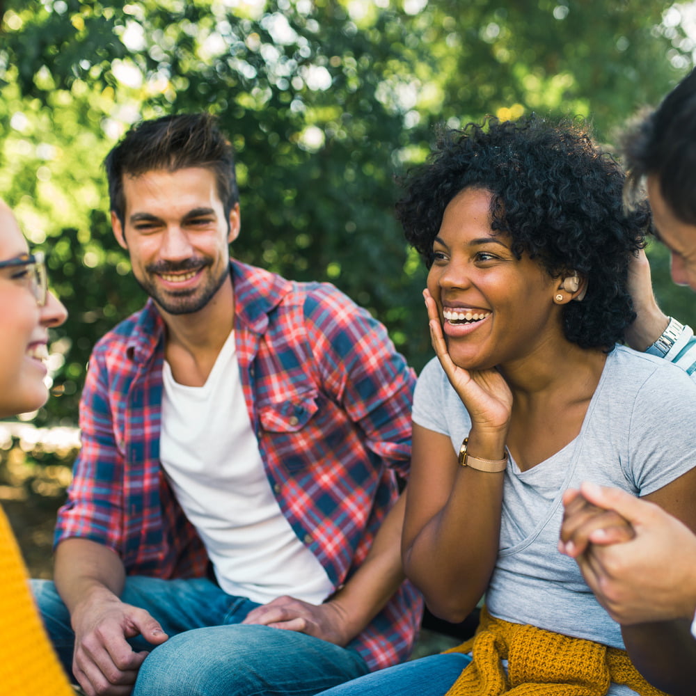 Young woman with hearing aid having fun with friends in park